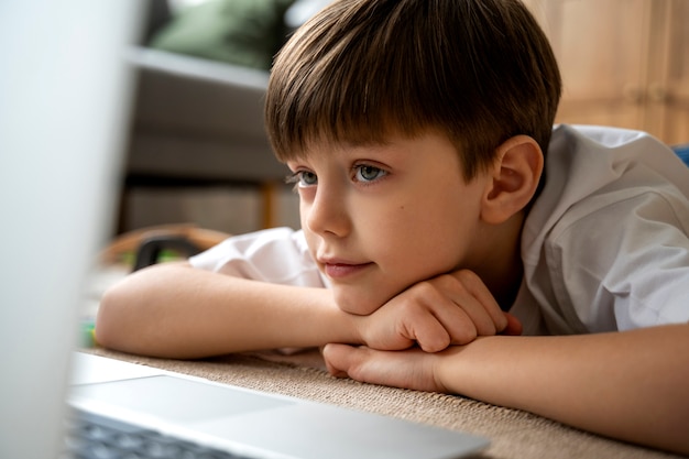 Kleiner junge der filme auf dem laptop anschaut 23 2150371771